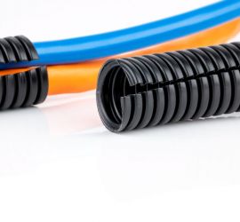 Een zwarte mantelbuis, met sleuf uitgevoerd, met op de achtergrond twee kabels die door een mantelbuis gevoerd worden.